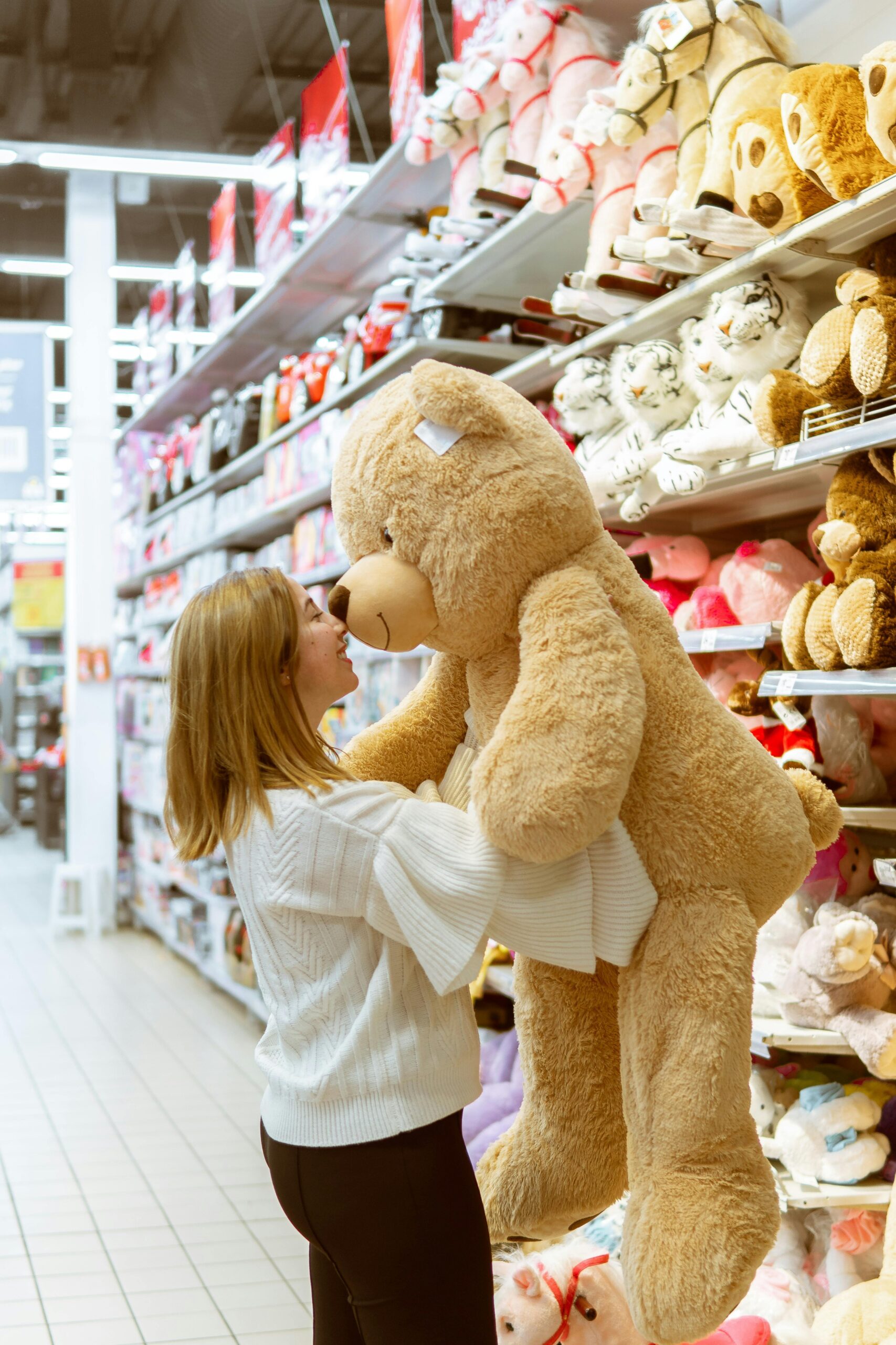 A woman in a toy store with a large teddy bear. Used to depict Customer Loyalty in retail.