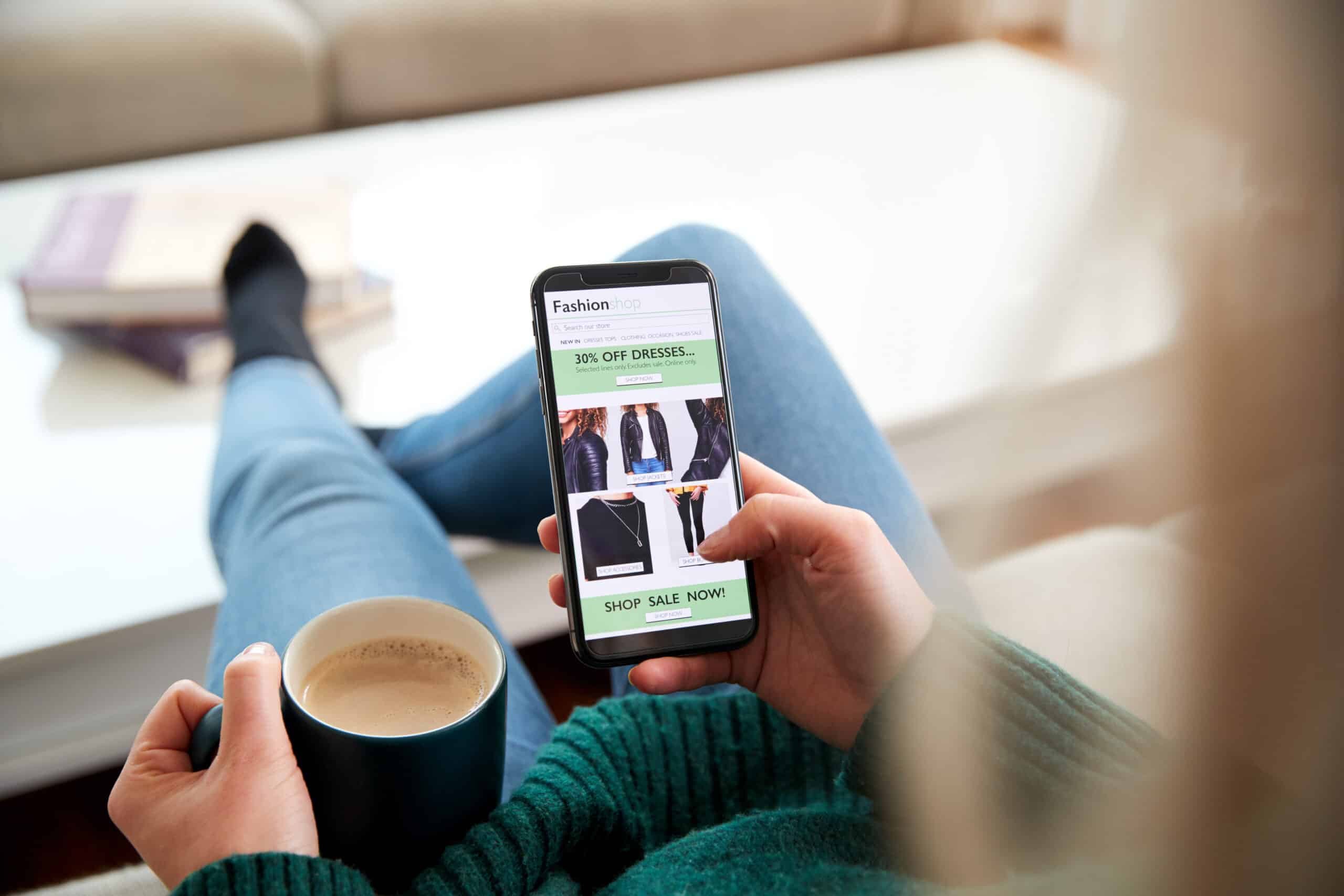 Person shopping fashion online with coffee